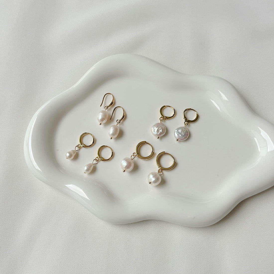 Woman wearing gold hoop earrings on a summer vacation beach — vacation jewelry trend 2026