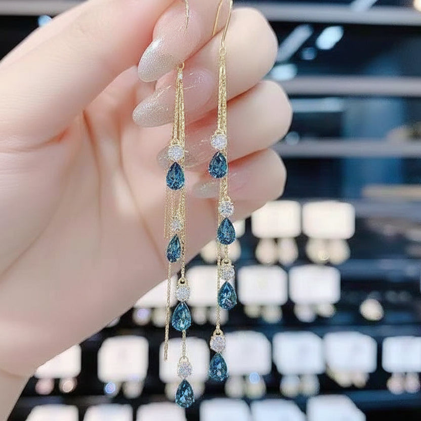 Blue crystal tassel ear line earrings with zircon drop, gold finish, held in hand