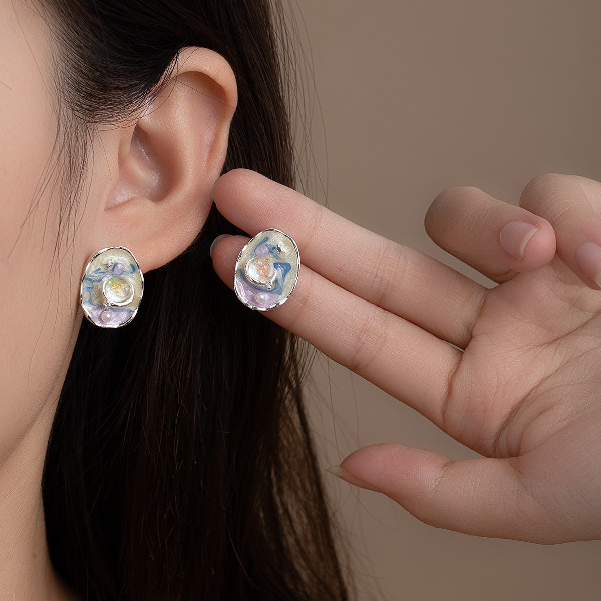 Blue and purple enamel stud earrings worn on ear, artistic design