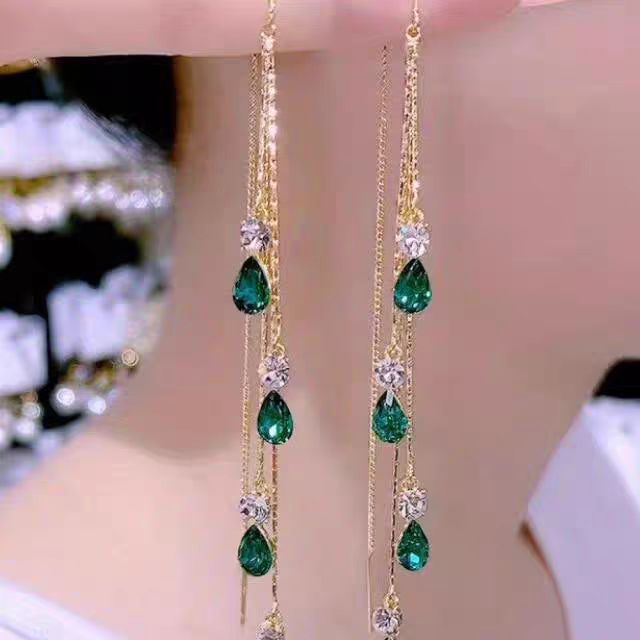 Green crystal tassel ear line earrings with gold finish, worn on ear

