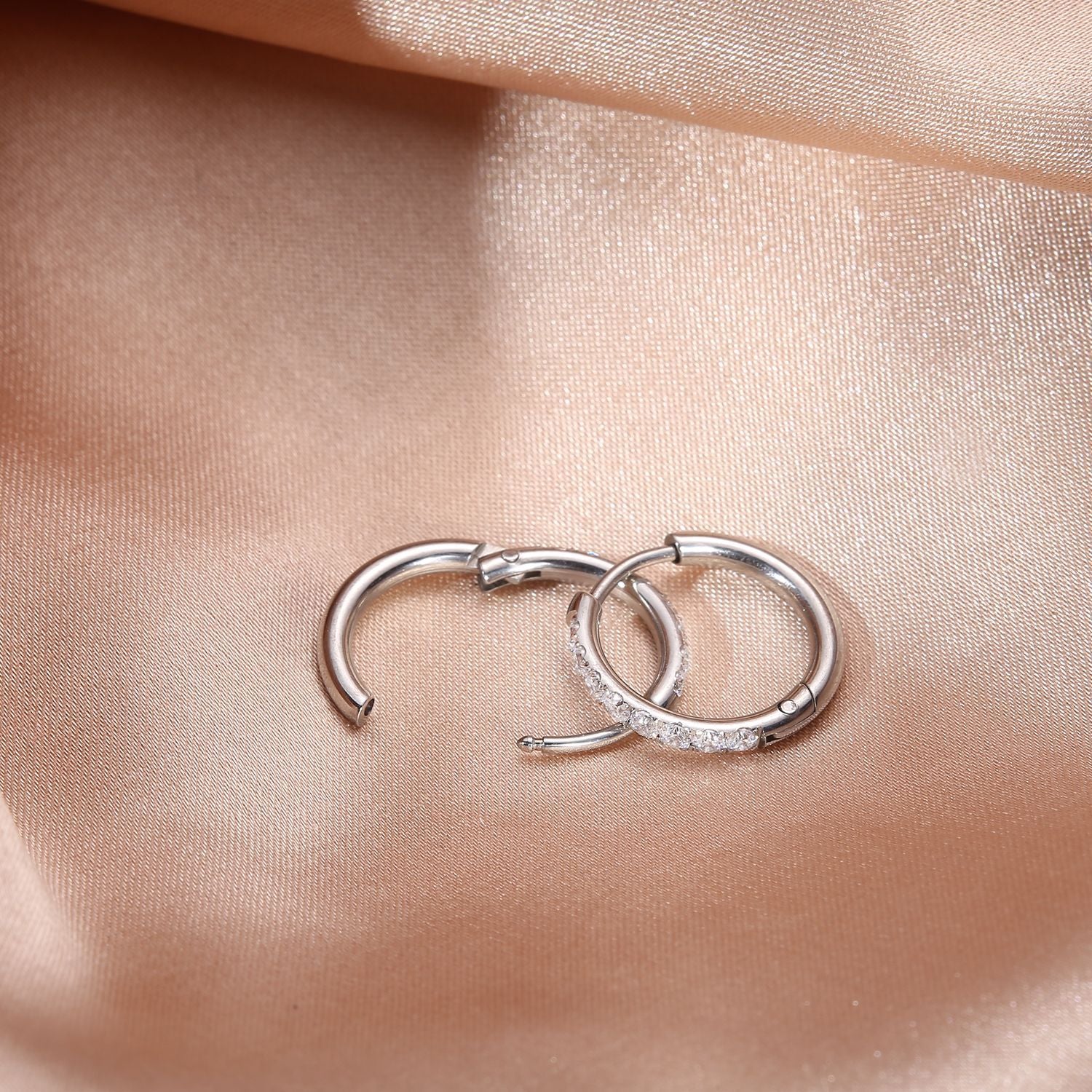 Silver titanium steel zirconia hoop earrings detail view on satin background